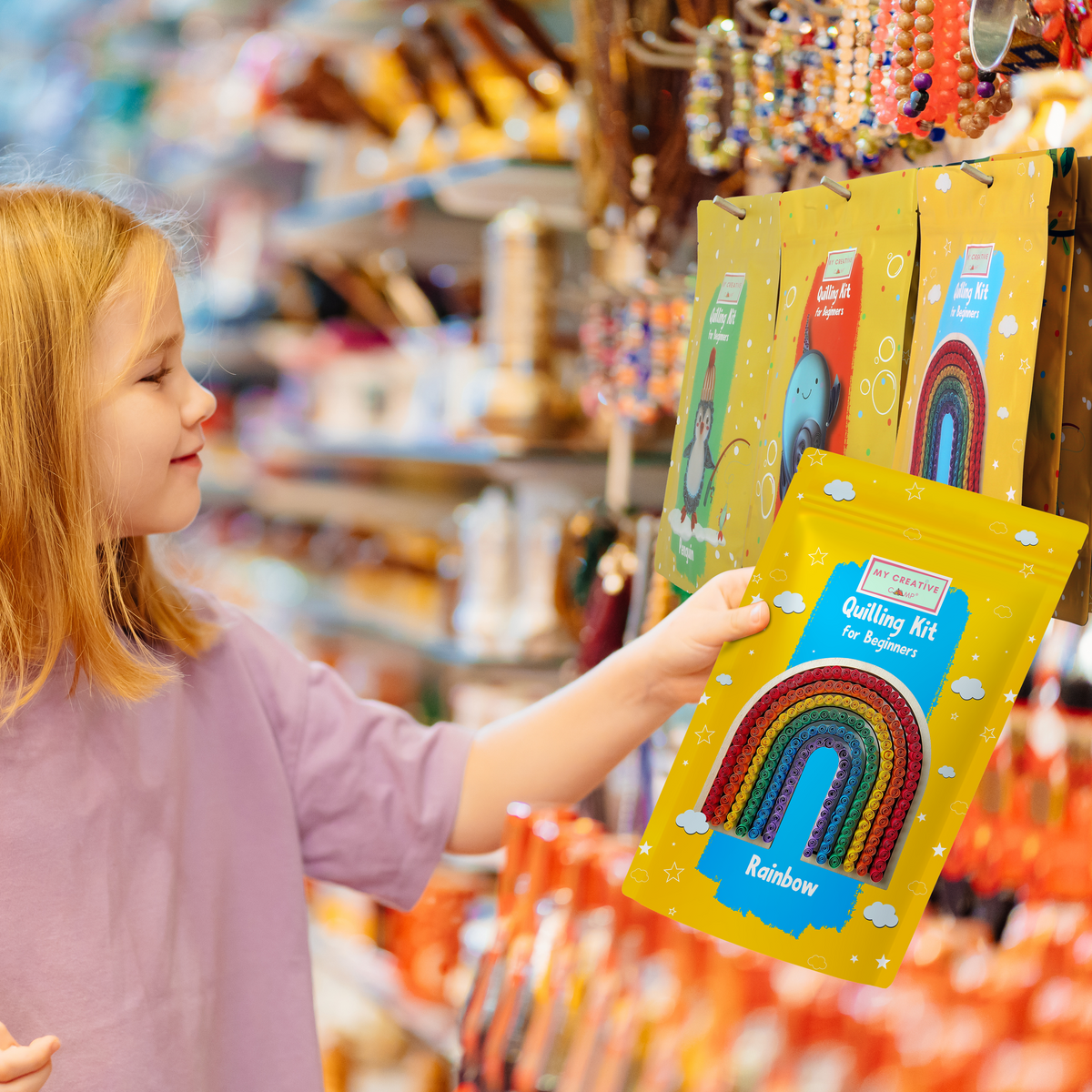 Child holding a rainbow paper quilling kit designed for beginner crafting projects
