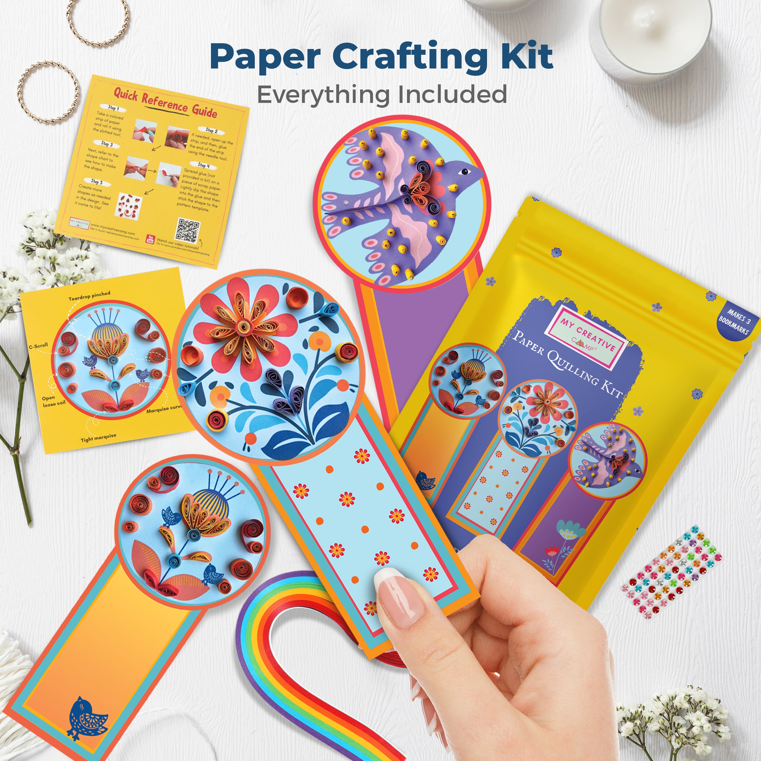 Paper crafting kit with colorful designs on a white surface
Top-down view of paper crafting kit with bookmarks, tools, and colorful quilling strips.
