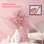 Living room with cherry blossom branches in a vase, framed artwork on the wall, and a white armchair. Display your finished artwork