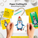 Paper crafting kit with penguin design, including cards and a completed craft, on a white surface.