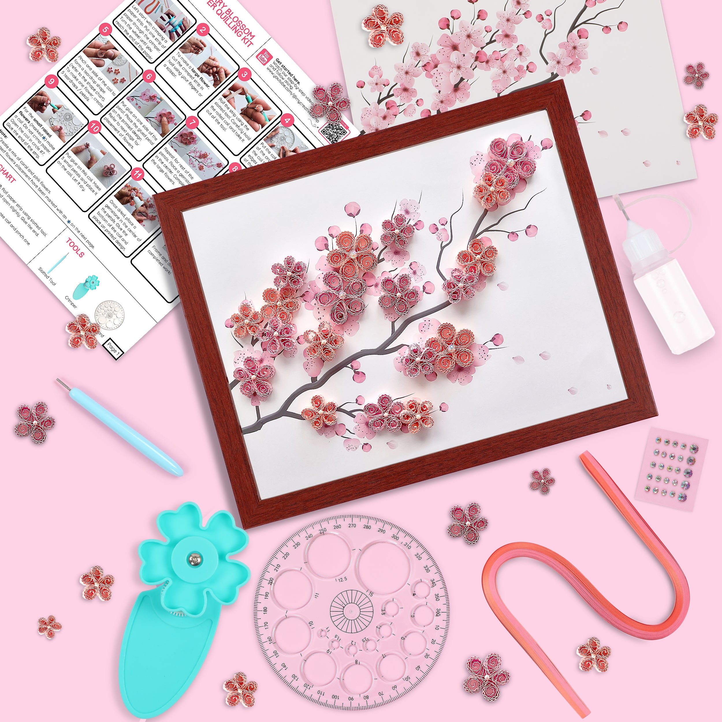 Artistic craft project with cherry blossom design, tools, and materials on a pink background