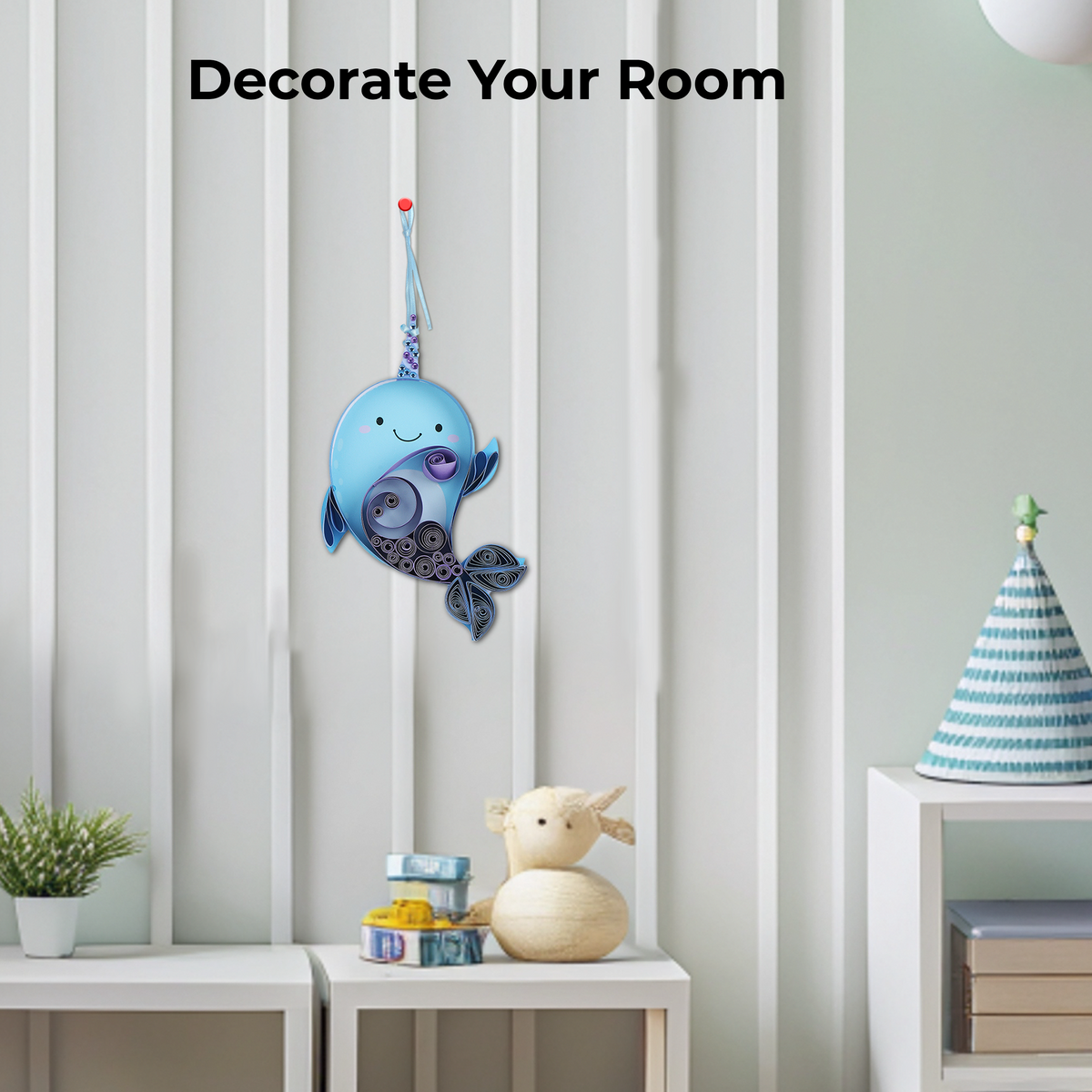 Decorative blue whale wall hanging in a room with a plant and small table.