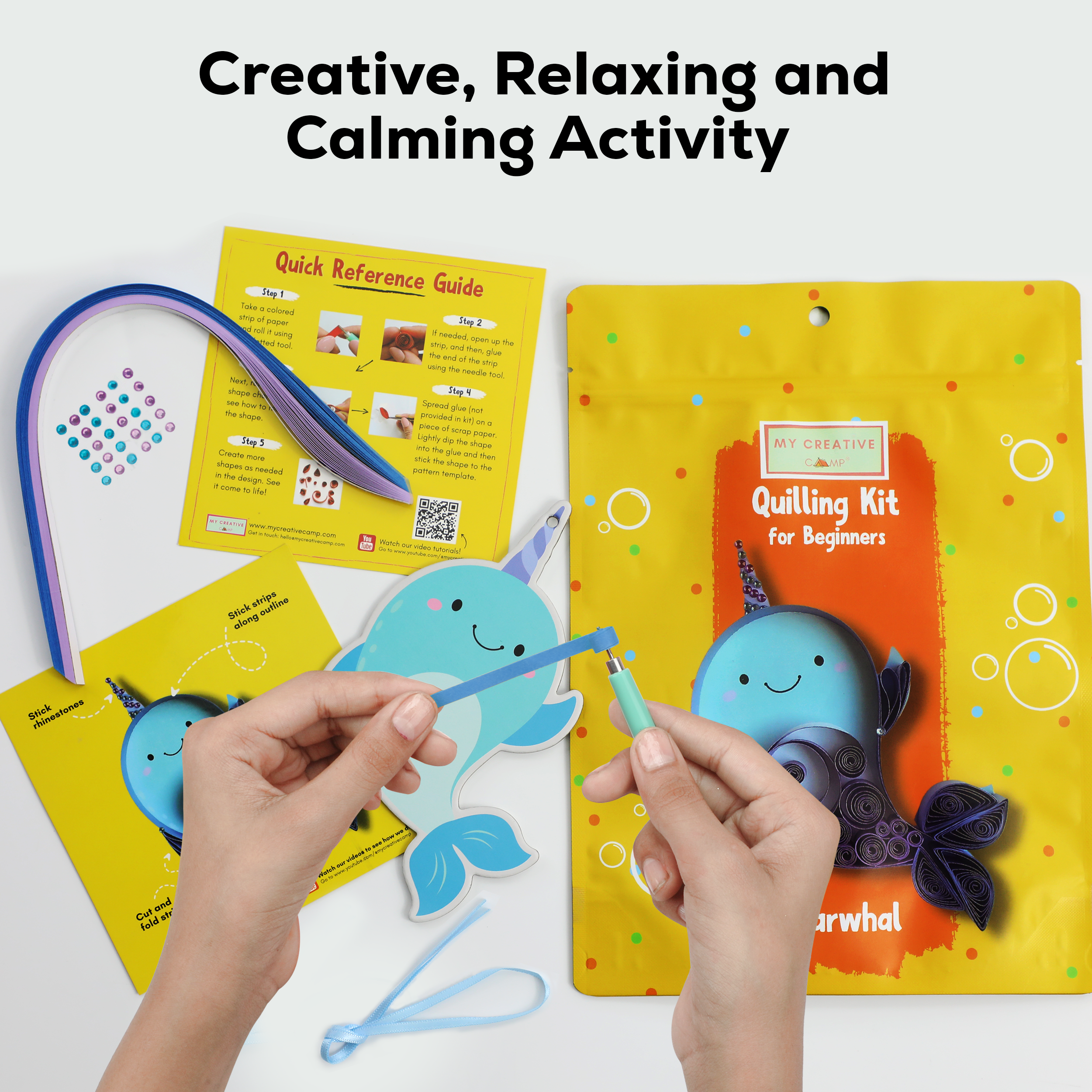 Quilling kit with whale design, reference guide, and text 'Creative, Relaxing and Calming Activity' on a white background.
Paper quilling kit with narwhal design, quilling tool, colorful paper strips, and accessories