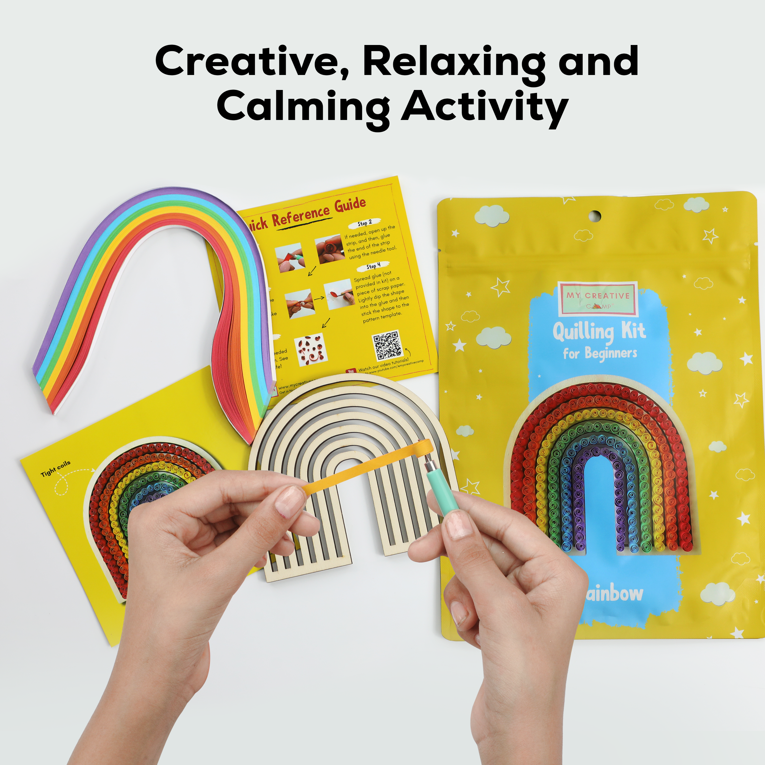 Quilling kit with rainbow design and hands using a tool on a white background
