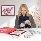 Woman working on a craft project with cherry blossom-themed materials and decorations.