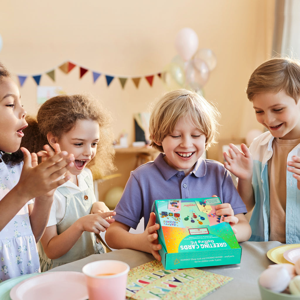 Children gathered around a table with a colorful box, likely at a birthday party.
Kids enjoying a creative paper quilling activity while making custom greeting cards